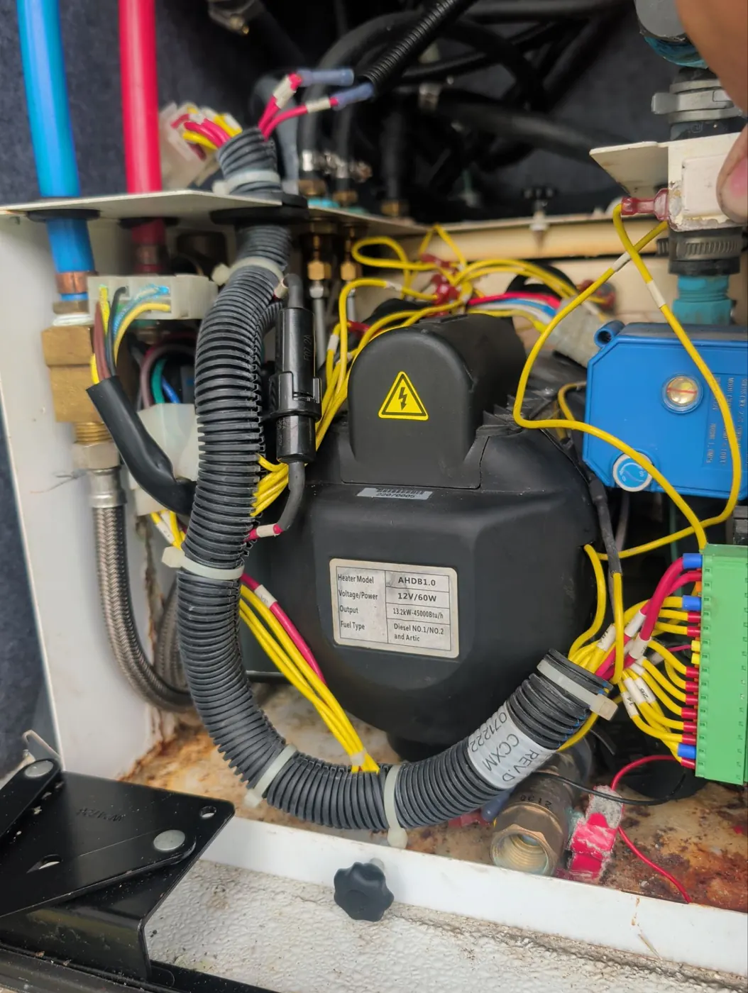 Diesel burner module in a hydronic heating bay, wiring harness and terminal block exposed during service