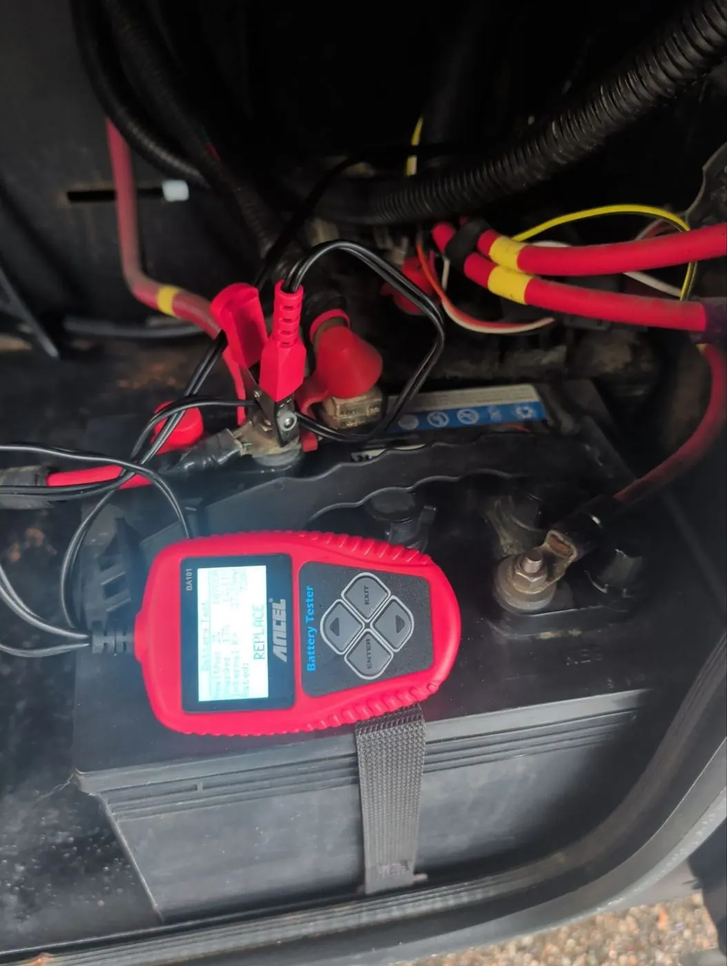 Battery tester clamped to an RV battery, reading its condition on site