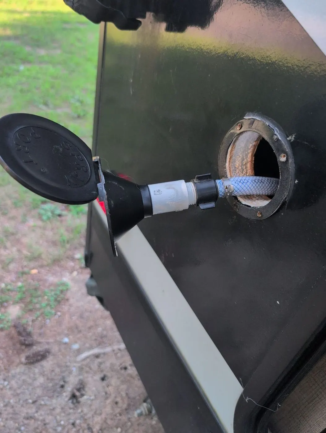 Exterior RV tank connection with a hose attached during service