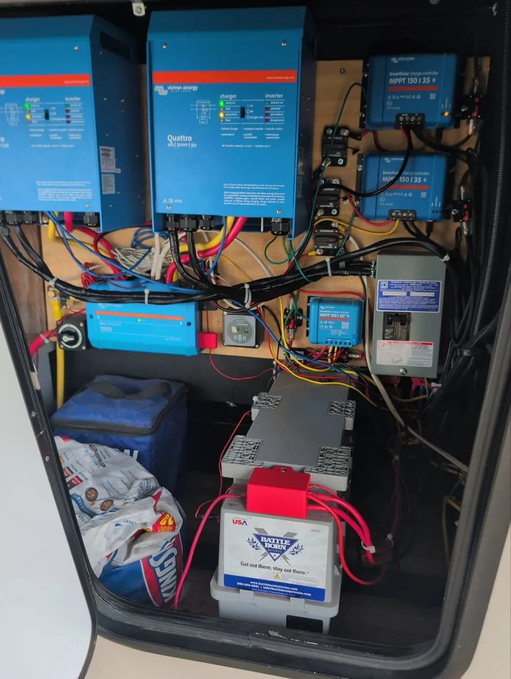 Victron Quattro inverter charger and MPPT controllers wired to Battle Born lithium batteries in a bay