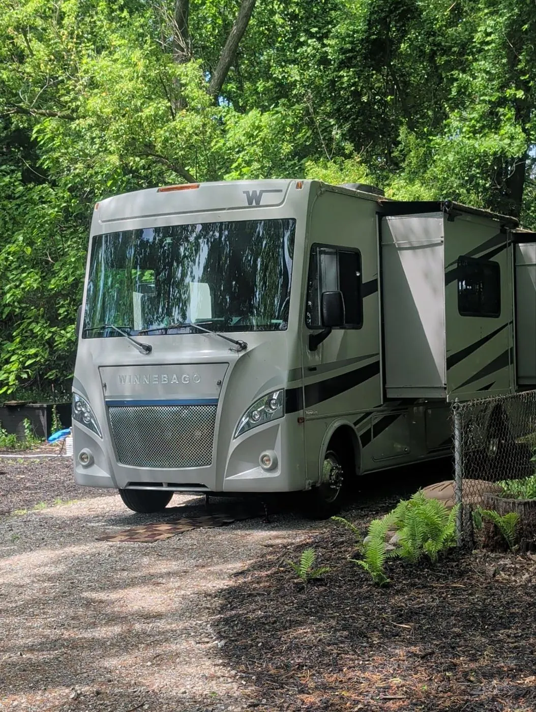 Class A motorhome parked among trees during an on-site service visit